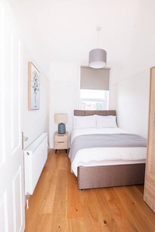 Small bedroom with single bed, wooden floor, white walls and pendant light fixture