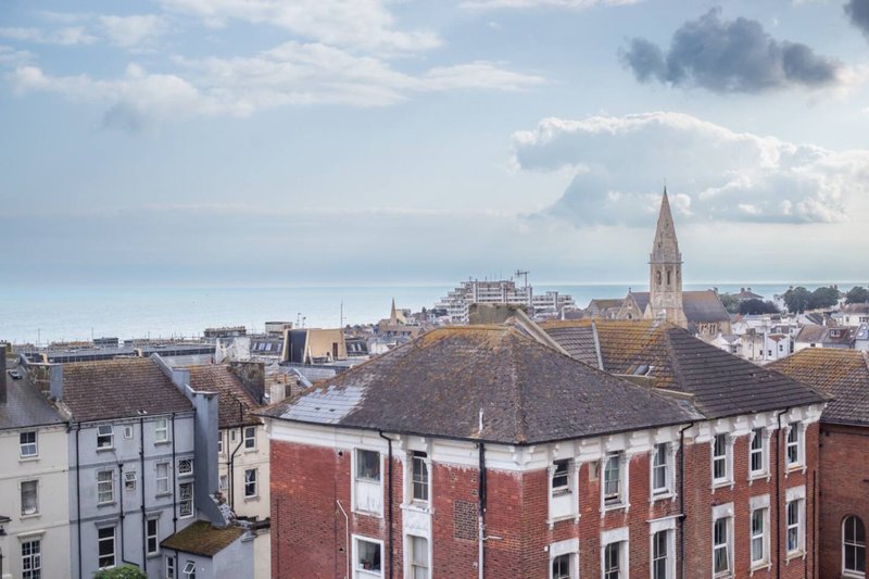 Elevated view of townscape with red brick buildings, church spire, and cloudy sky