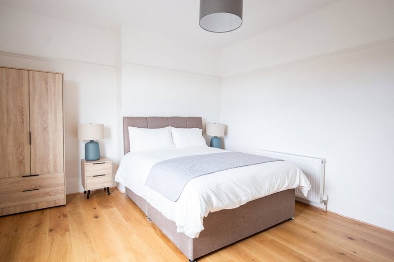 Bright modern bedroom with double bed, wooden wardrobe, bedside table and ceiling light