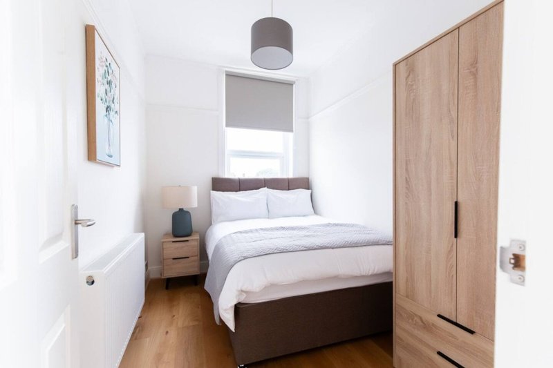 Bright modern bedroom with double bed, wooden wardrobe, nightstand, and pendant light