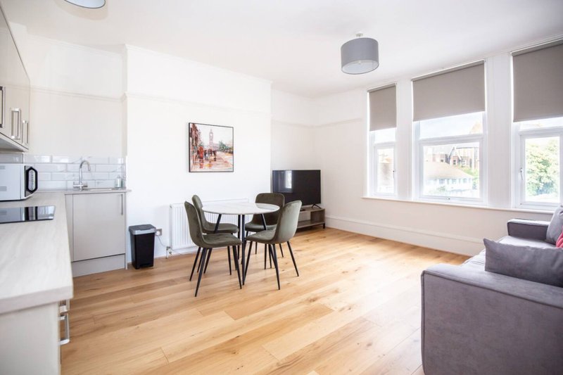 Open-plan living area with kitchen, dining table, sofa and large windows