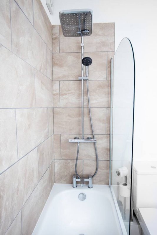 Modern bathroom shower with rainfall showerhead, handheld spray, and glass enclosure door