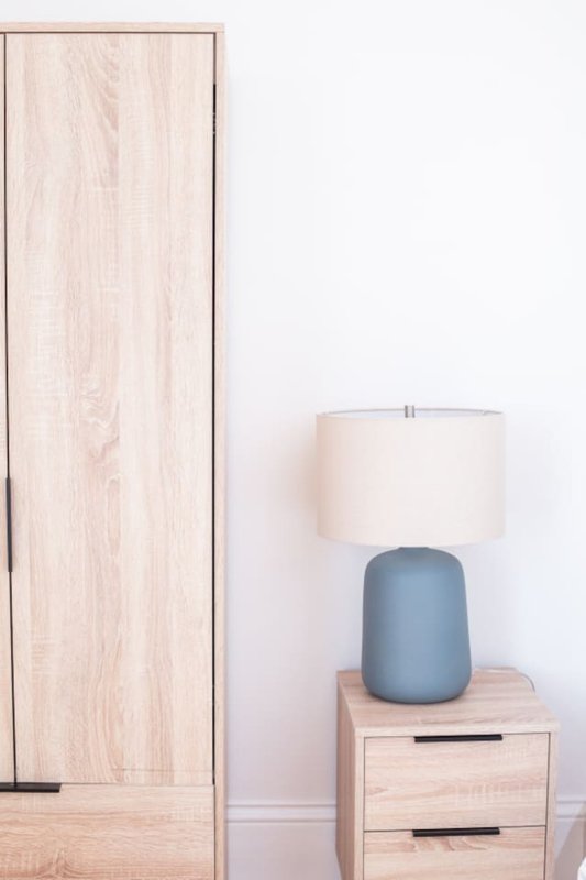 Bedroom corner with wooden wardrobe, bedside table with blue ceramic lamp