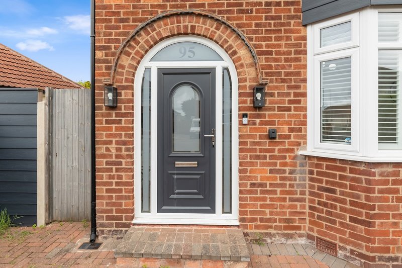 Red brick house exterior with black front door, white frame and brick porch entrance