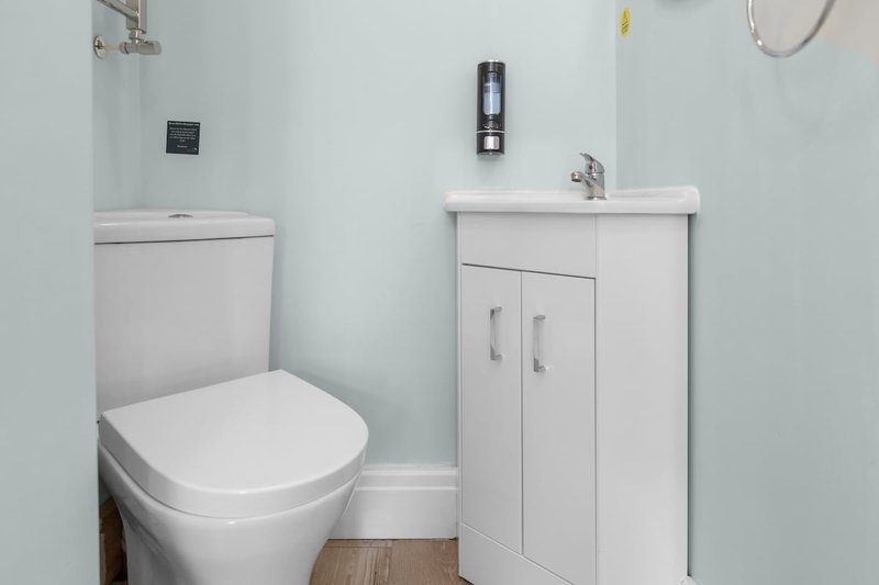 Small bathroom with white toilet, vanity sink, and light blue walls