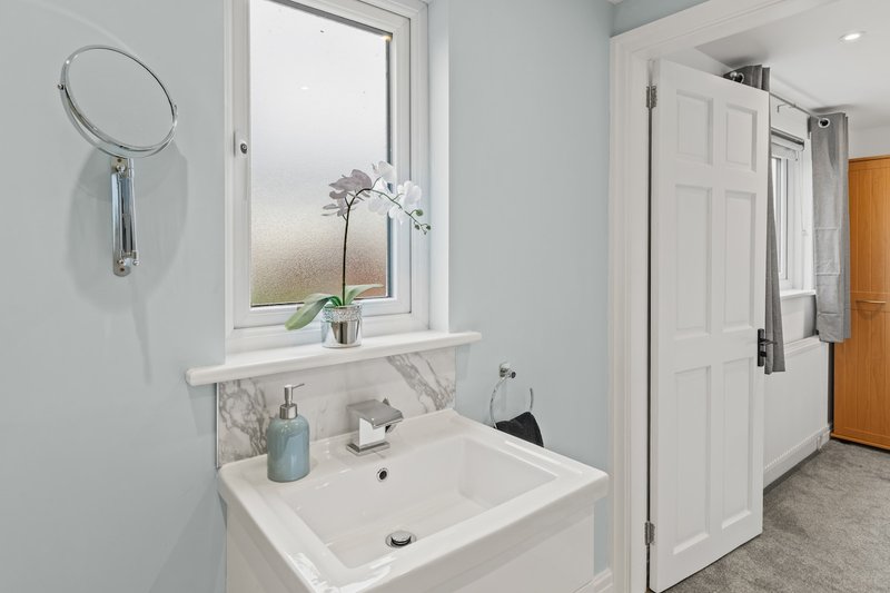 Modern bathroom with white sink, mirror, window and shower enclosure
