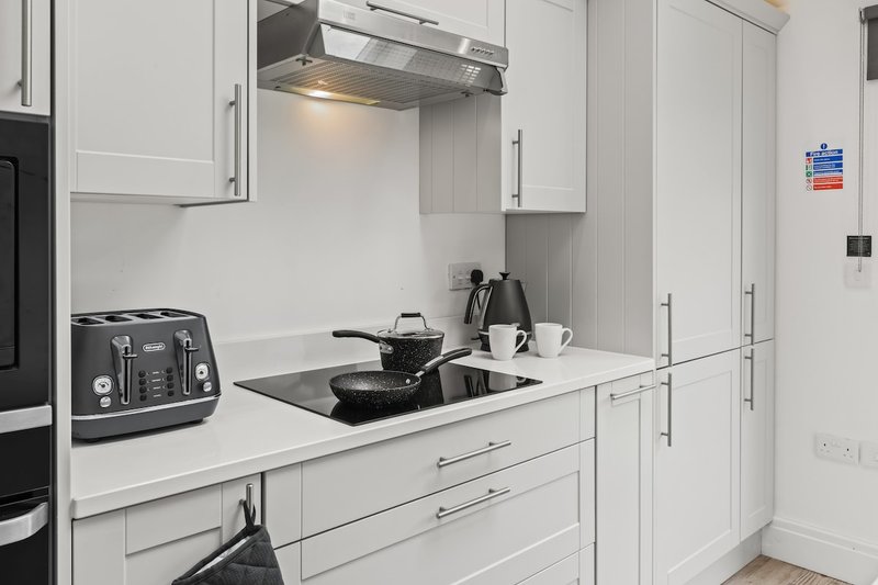 Modern white kitchen with stainless steel appliances, white cabinetry, and countertop items