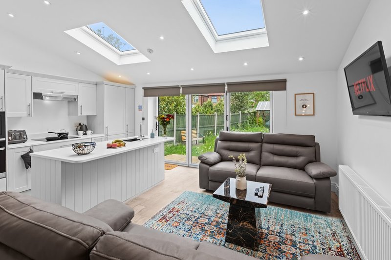 Open-plan kitchen and living room with skylights, grey sofa, island counter and garden view