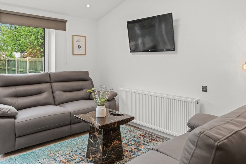 Modern living room with gray leather sofas, wall-mounted TV, marble coffee table and garden view
