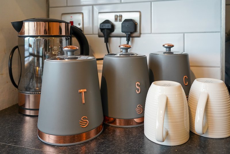 Kitchen counter with gray kettle, matching canisters, and cream-colored toaster appliances