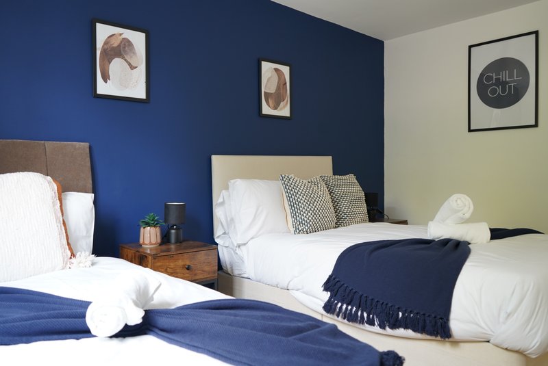 Twin bedroom with blue accent wall, wooden bedside tables, and framed dog artwork