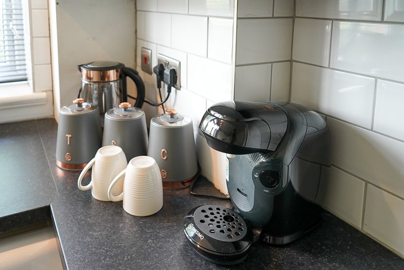 Kitchen counter with kettle, coffee maker, mugs and appliances