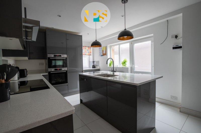 Modern kitchen with grey cabinetry, island, pendant lights and large windows.