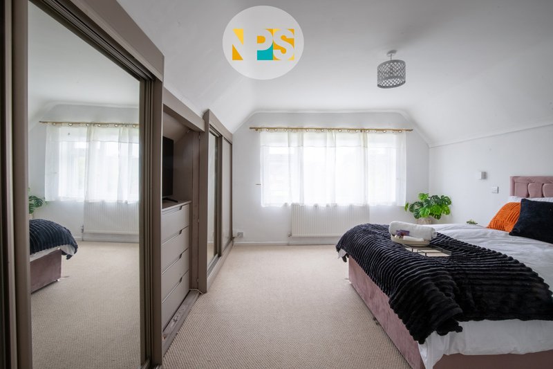 Bright bedroom with king size bed, mirrored wardrobe, colourful ceiling light and windows with natural light