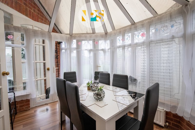 Bright dining room 2 with white table, black chairs, large windows and skylights.