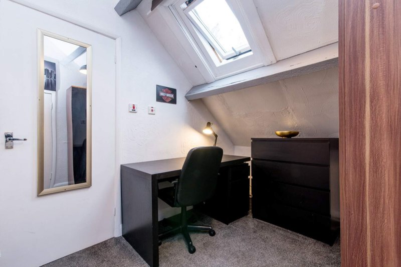 Modern home office with black desk, office chair, skylight and mirrored door