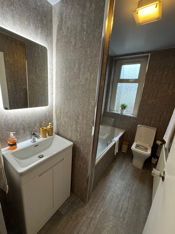 Modern bathroom with white vanity, illuminated mirror, shower enclosure and toilet