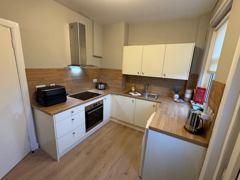 Modern kitchen with white units, wooden worktops, integrated appliances and breakfast bar