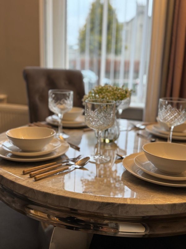 Dining table set for three with place settings, glasses, and potted plant centerpiece