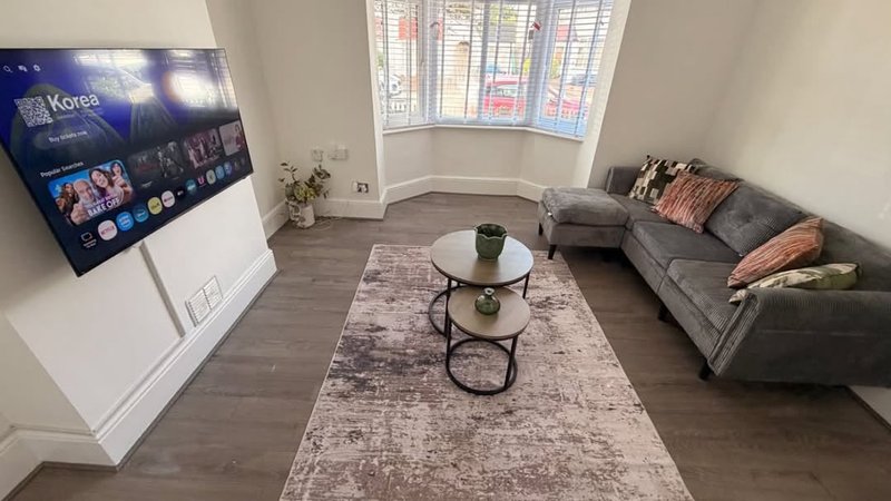 Modern living room with gray sofa, coffee table, TV, and large windows