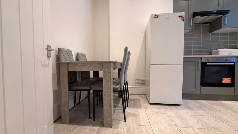 Modern kitchen and dining area with white appliances, concrete dining table and grey chairs