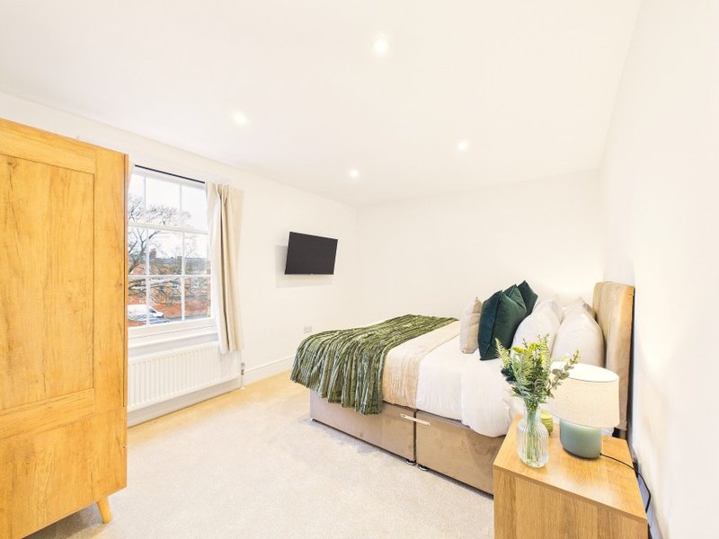 Bright bedroom with double bed, wooden furniture, wall-mounted TV and garden view