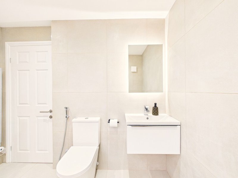Modern bathroom with white fixtures, wall-mounted sink, toilet, and mirror above vanity