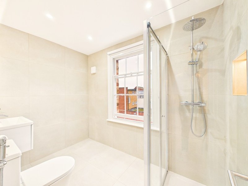 Modern bathroom with shower enclosure, toilet, sink and window with natural light