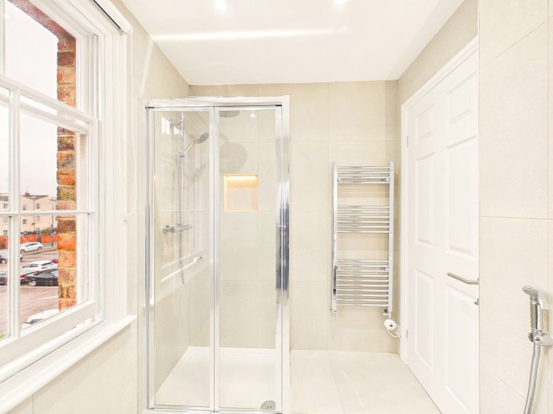 Modern bathroom with shower enclosure, heated towel rail, and window with brick exterior view