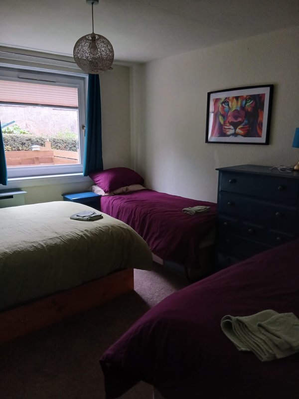 Bedroom with two beds, purple bedding, pendant light, window with view, and framed wall art