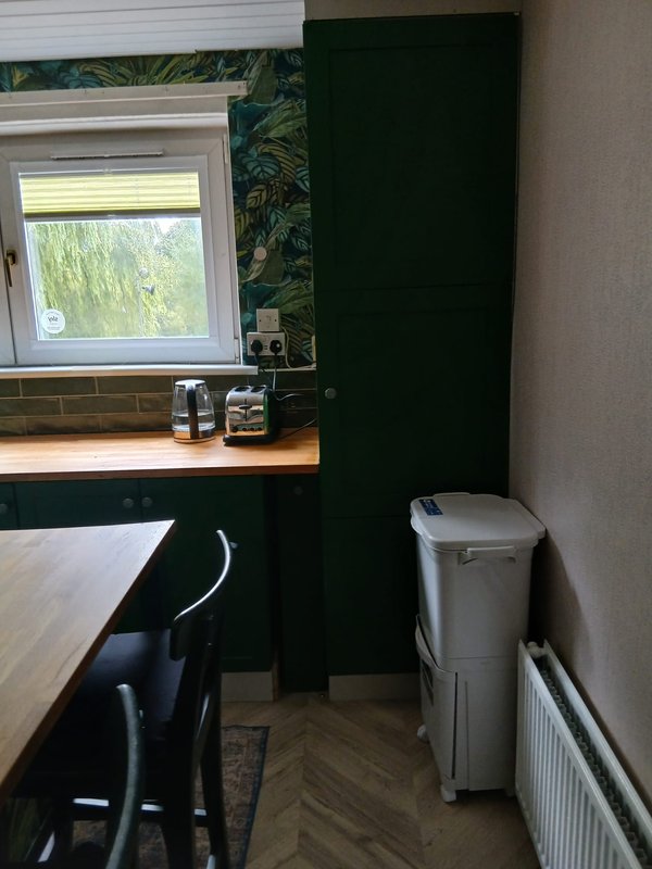 Small kitchen with dark cabinetry, wooden counter, window, and herringbone flooring