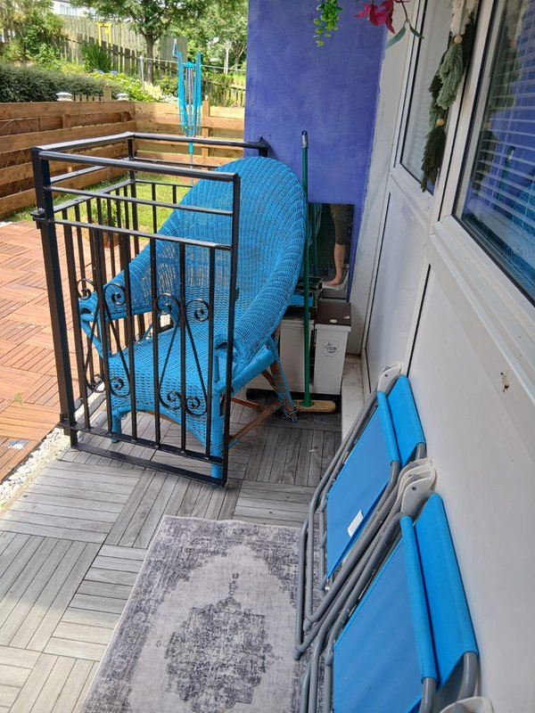 Outdoor patio area with blue furniture, decking, and purple-painted wall beside property