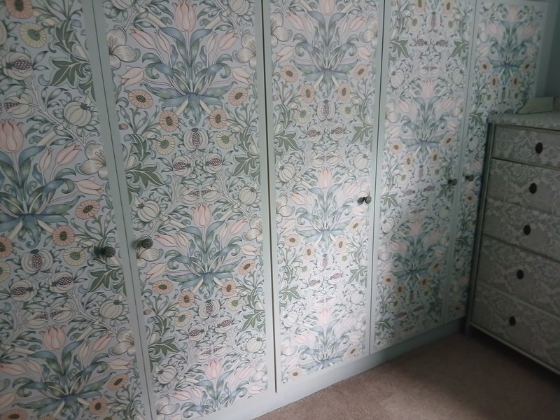 Built-in wardrobe with floral patterned doors and grey wooden chest of drawers