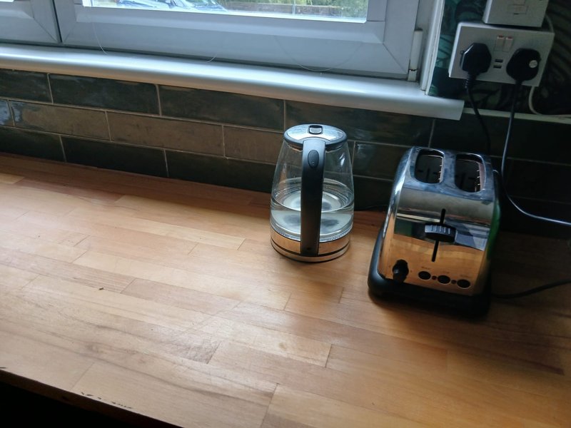 Kitchen countertop with kettle, toaster, and window overlooking garden