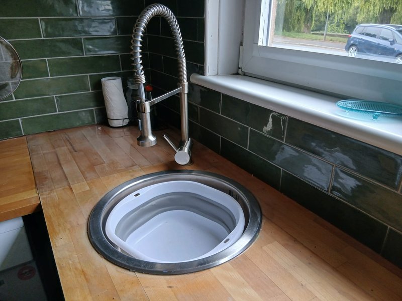 Kitchen sink with pull-down tap, green tile backsplash and wooden countertop