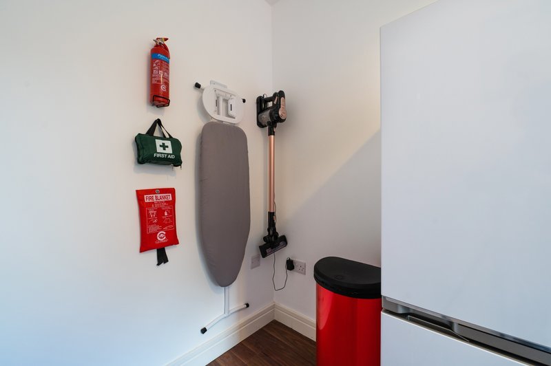 Utility corner with ironing board, fire extinguisher, and household storage items