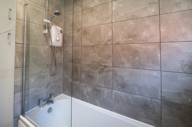 Modern bathroom with walk-in shower enclosure, white bathtub and tiled walls
