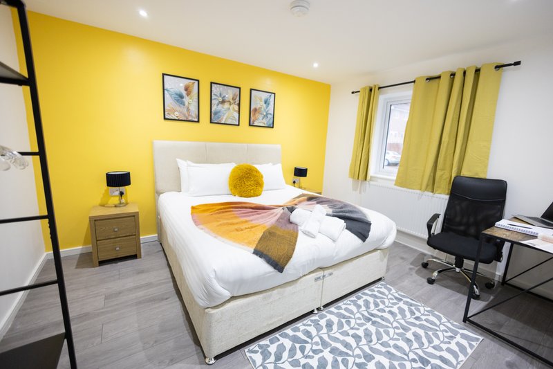 Bright yellow bedroom with double bed, white bedding, desk area, and coordinating yellow curtains