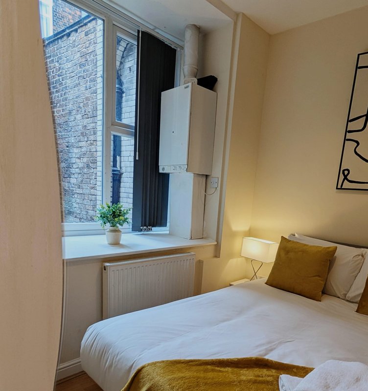 Bright bedroom with double bed, window seat, radiator and warm yellow walls