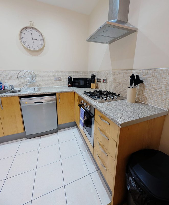 Modern kitchen with wooden cabinets, gas hob, dishwasher, tiled splashback and white flooring