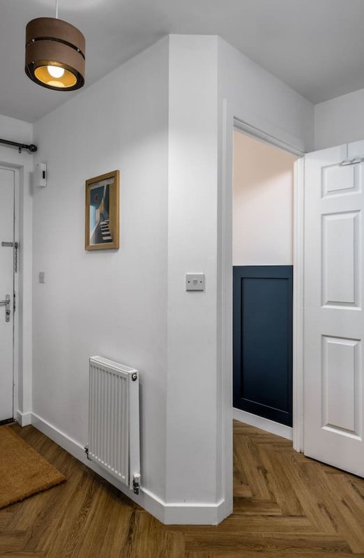 Modern hallway with white walls, wooden floor, pendant light and radiator