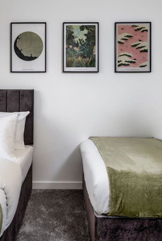 Bedroom with double bed, framed artwork above headboard, and green throw blanket