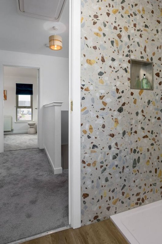 Modern bathroom with terrazzo wall, grey floor, white partition wall and pendant light