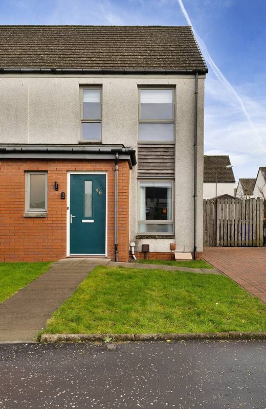 Modern semi-detached house with brick extension, green door, driveway and front garden
