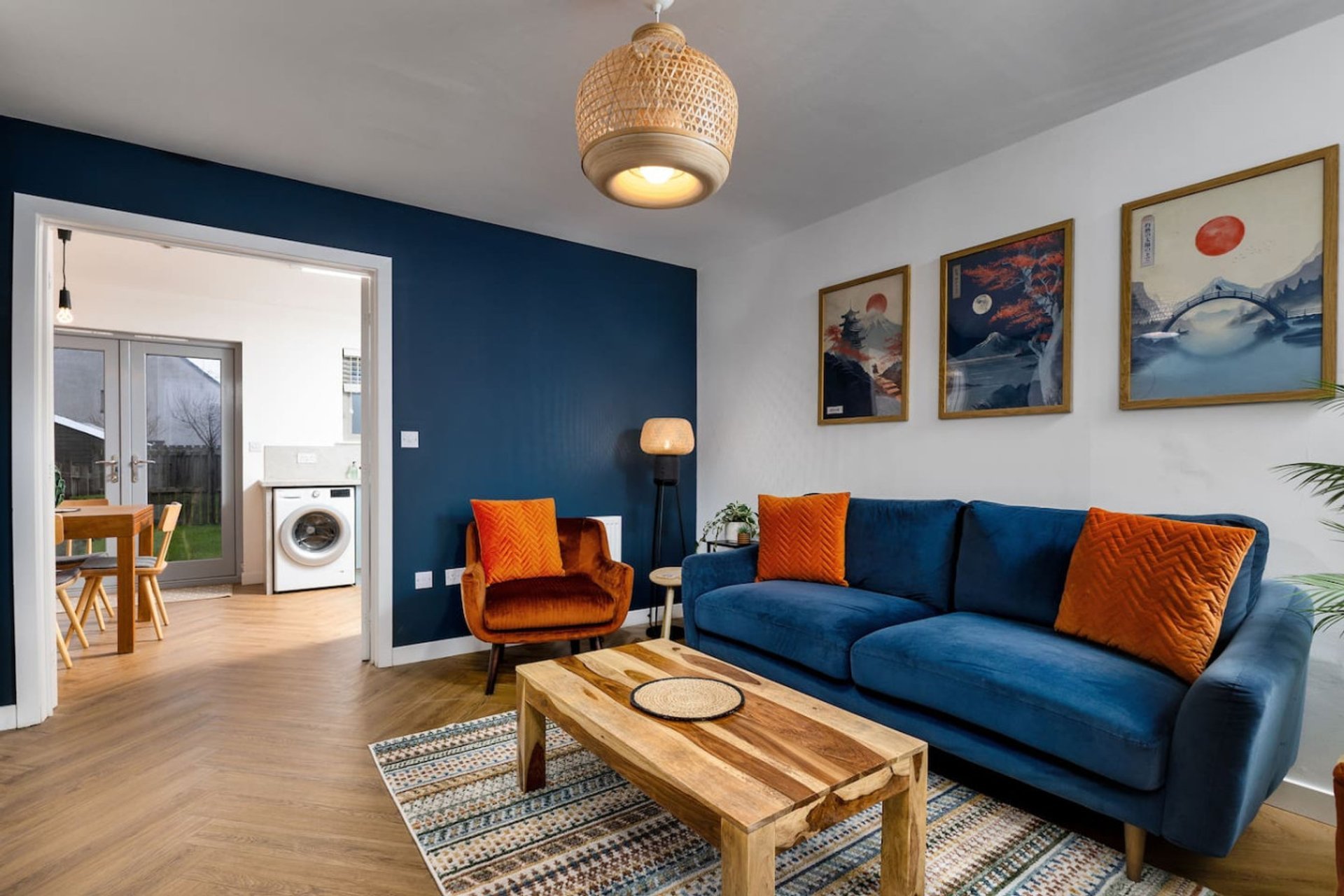 Modern living room with blue sofa, orange accent chair, wooden coffee table and framed wall art