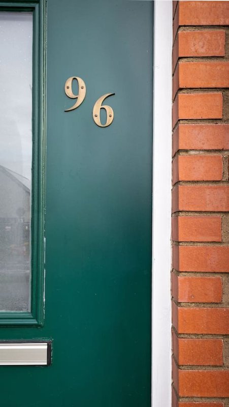 Green front door with house number 96 and red brick exterior wall