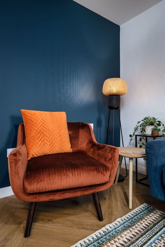 Modern living room with terracotta velvet armchair, floor lamp, potted plant and geometric rug