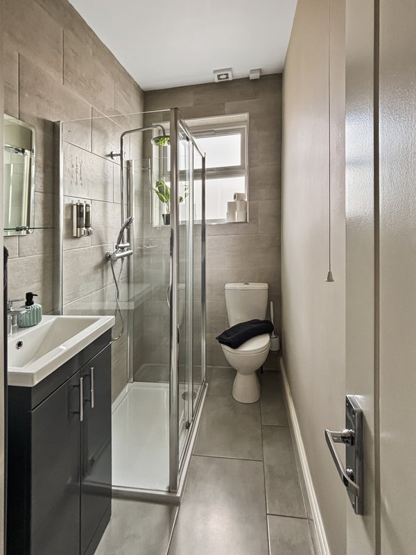 Modern bathroom with walk-in shower, sink vanity, toilet and tiled walls