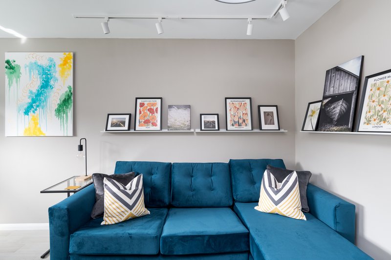 Modern living room with blue sectional sofa, decorative pillows, and framed artwork on walls