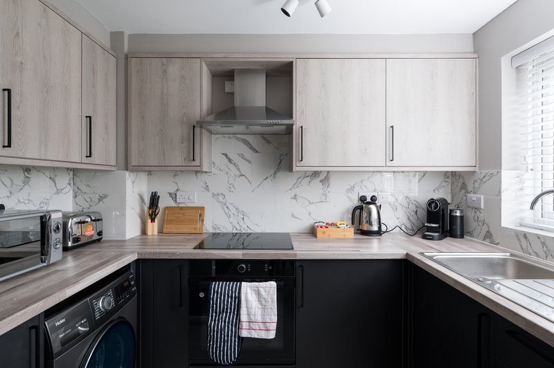 Modern kitchen with marble backsplash, black and white cabinetry, stainless steel appliances and island